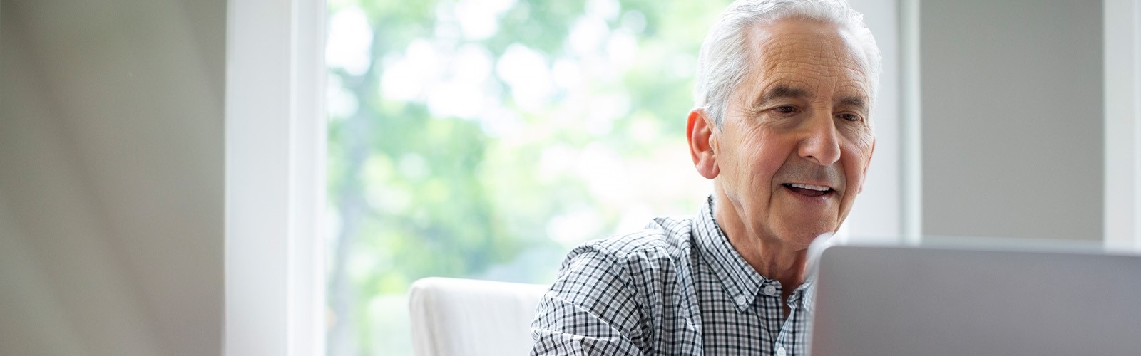 An older man sat at a desk, researching things on his computer